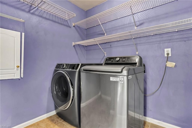 laundry room with washing machine and clothes dryer, laundry area, tile patterned floors, and baseboards