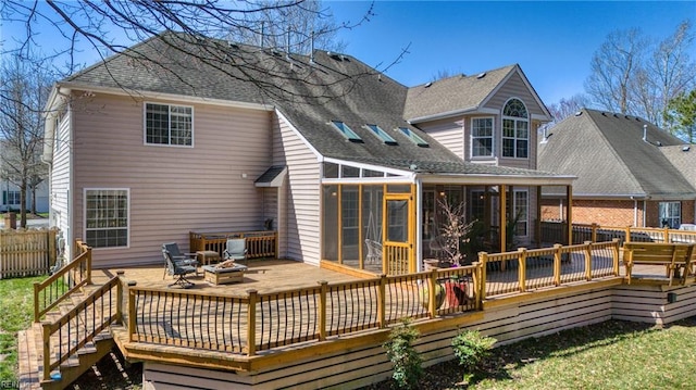 back of house with a wooden deck, a fire pit, fence, and a sunroom