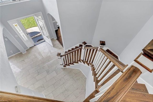 staircase with baseboards, arched walkways, and marble finish floor