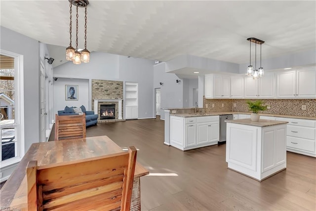 kitchen featuring a glass covered fireplace, dark wood finished floors, vaulted ceiling, white cabinetry, and open floor plan