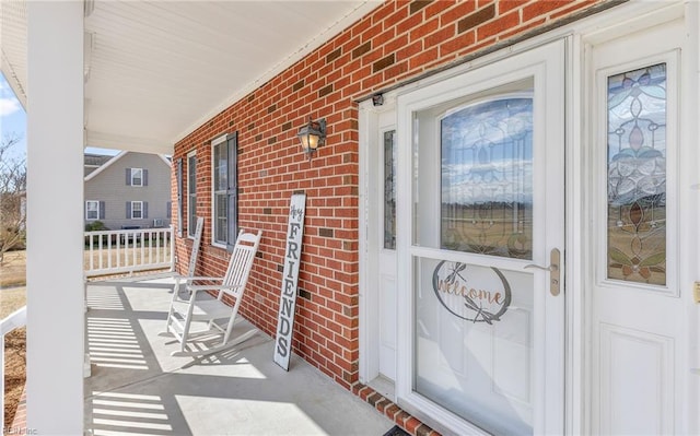 property entrance featuring brick siding and a porch