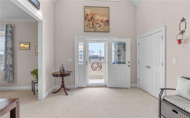 entryway featuring ornamental molding, baseboards, and light carpet