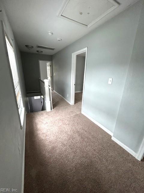 unfurnished room with attic access, baseboards, and light carpet