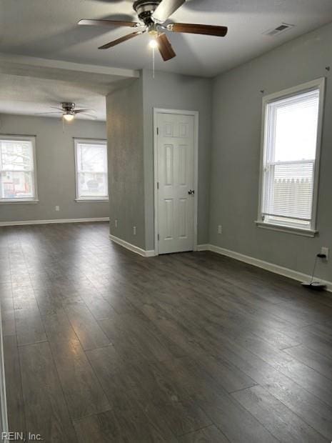 empty room featuring dark wood-style floors, visible vents, ceiling fan, and baseboards