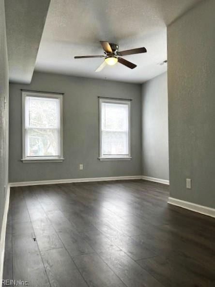 unfurnished room with baseboards, a ceiling fan, and dark wood-style flooring