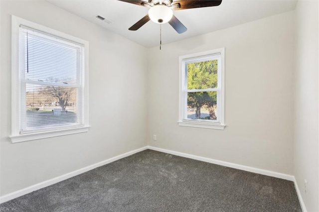 unfurnished room featuring baseboards, visible vents, dark carpet, and ceiling fan