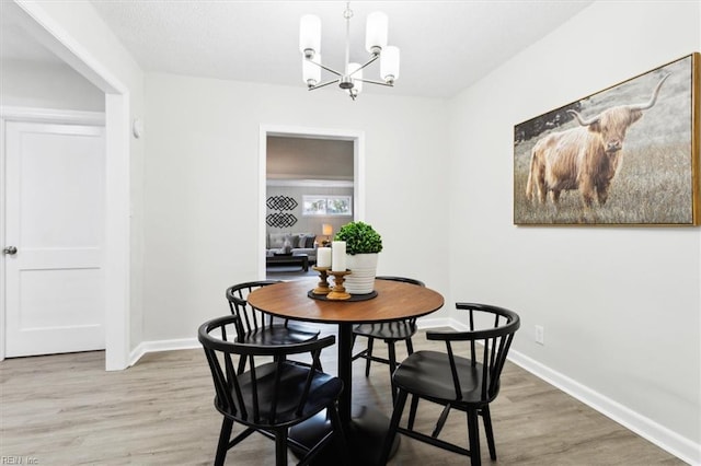 dining space featuring baseboards, an inviting chandelier, and light wood finished floors