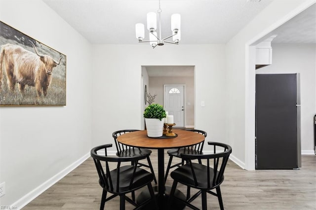 dining area with light wood-style floors, baseboards, and a chandelier