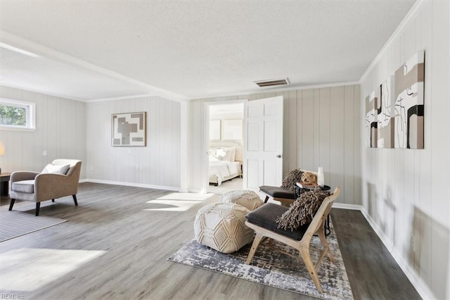 sitting room featuring visible vents, crown molding, baseboards, and wood finished floors