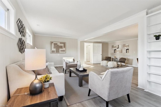 living area featuring built in features, wood finished floors, baseboards, and ornamental molding