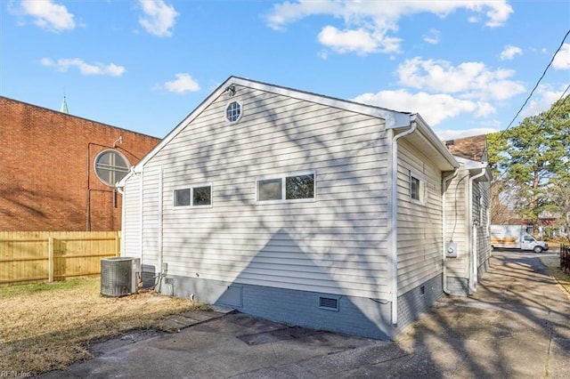 view of property exterior with crawl space, central air condition unit, and fence