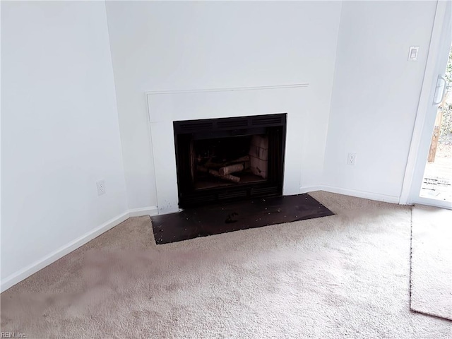 interior details with a fireplace with flush hearth, carpet, and baseboards