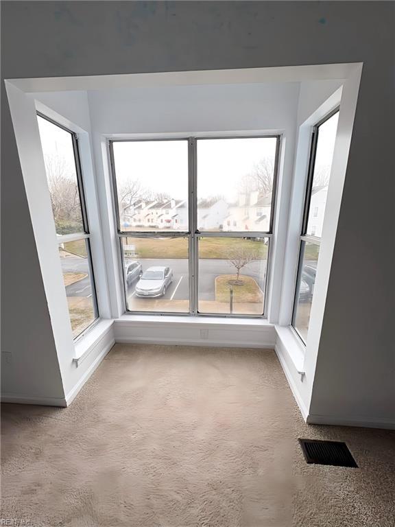 carpeted empty room featuring baseboards and visible vents