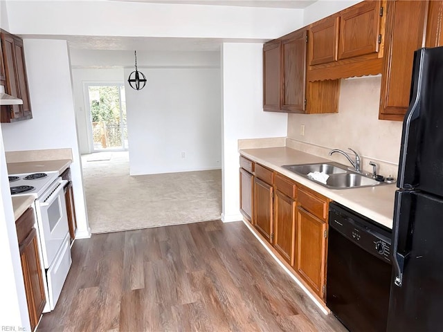 kitchen featuring brown cabinets, dark wood-type flooring, black appliances, a sink, and light countertops