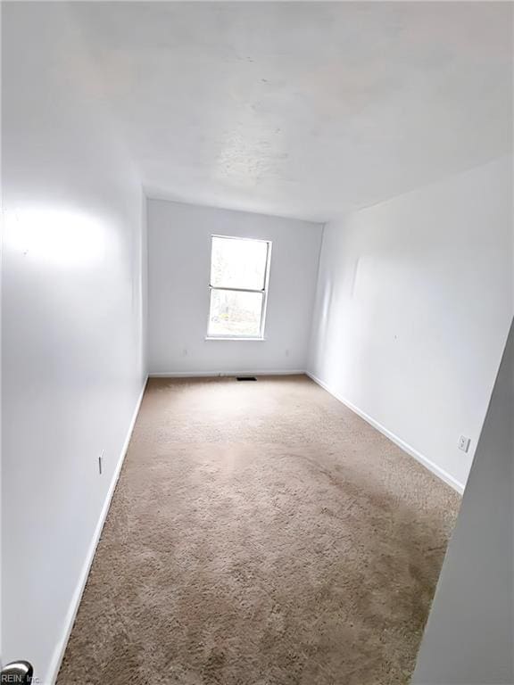 empty room featuring baseboards and carpet