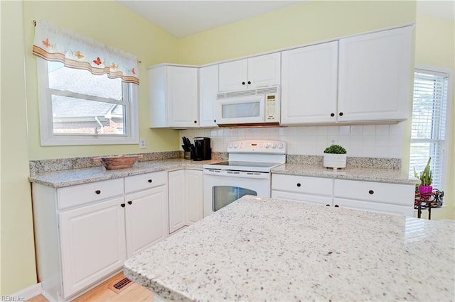 kitchen featuring decorative backsplash, white appliances, white cabinets, and plenty of natural light