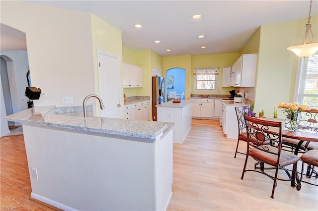 kitchen featuring a peninsula, arched walkways, a sink, white cabinetry, and white electric range