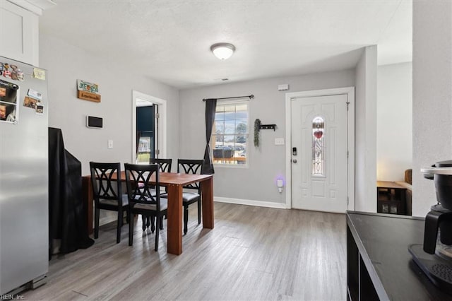 dining area featuring baseboards, a textured ceiling, and light wood finished floors