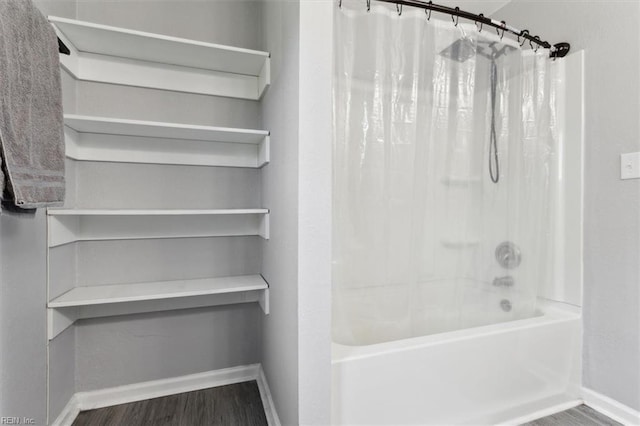 full bath featuring baseboards, wood finished floors, and shower / tub combo