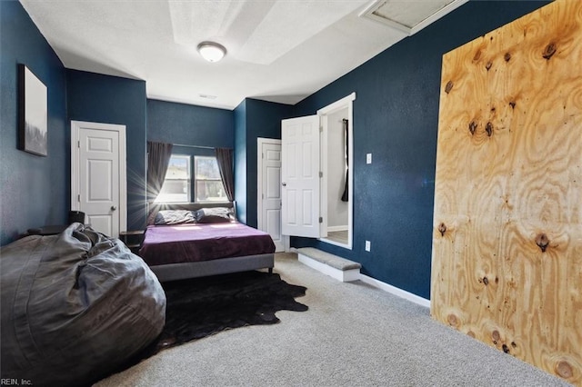 bedroom featuring attic access, carpet, baseboards, and a textured wall