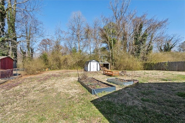 view of yard with an outdoor structure, a vegetable garden, a storage unit, and fence