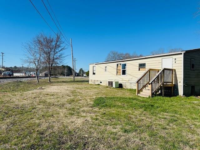 back of property with a lawn and central AC