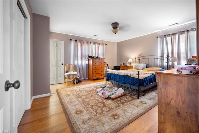 bedroom with light wood-type flooring, multiple windows, baseboards, and ceiling fan