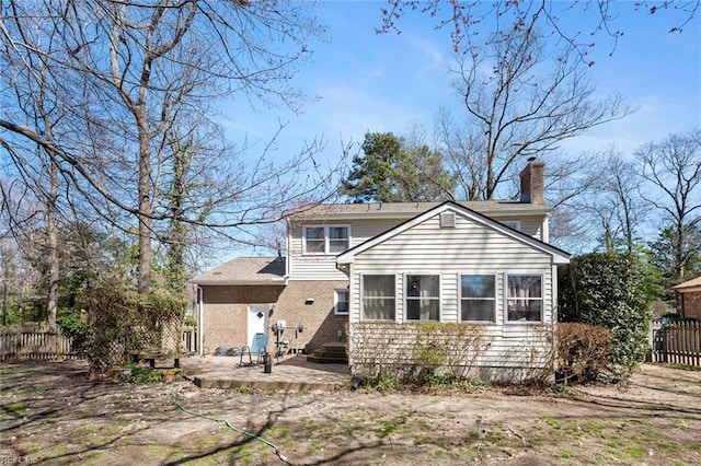 back of property featuring brick siding, a patio area, a chimney, and fence