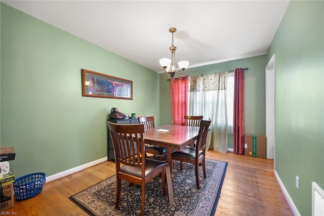 dining area with an inviting chandelier, wood finished floors, baseboards, and visible vents