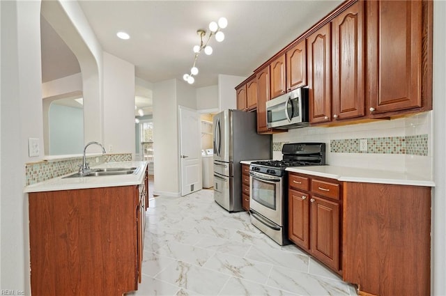 kitchen with backsplash, light countertops, marble finish floor, stainless steel appliances, and a sink