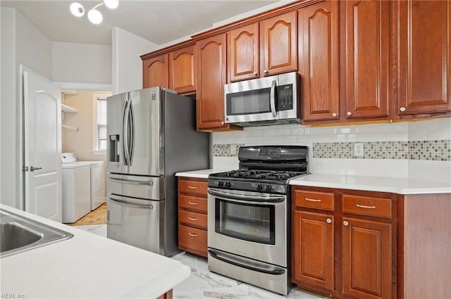 kitchen featuring stainless steel appliances, marble finish floor, light countertops, and washing machine and clothes dryer