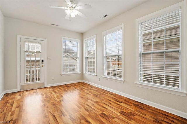 unfurnished dining area featuring light wood finished floors, visible vents, baseboards, and a ceiling fan