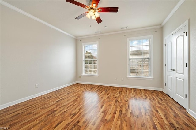 unfurnished room with wood finished floors, visible vents, baseboards, ceiling fan, and crown molding