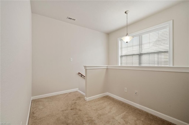 carpeted spare room featuring visible vents and baseboards