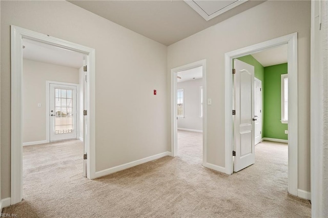 hall featuring attic access, carpet, and baseboards