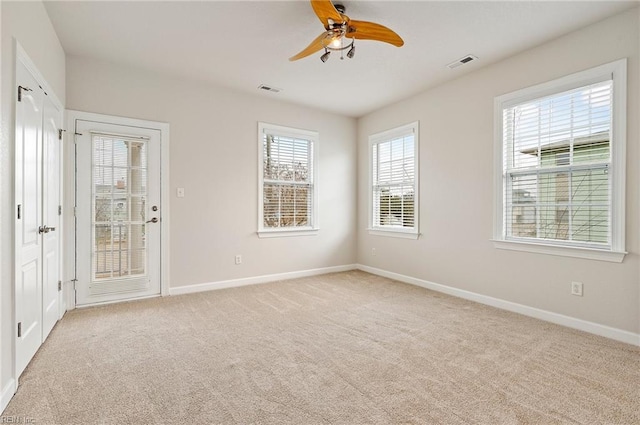 empty room featuring ceiling fan, baseboards, visible vents, and light carpet