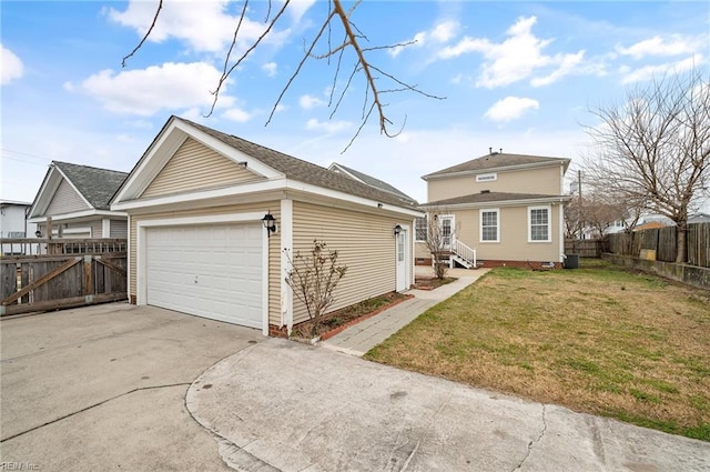 exterior space featuring fence, concrete driveway, a lawn, an outbuilding, and an attached garage