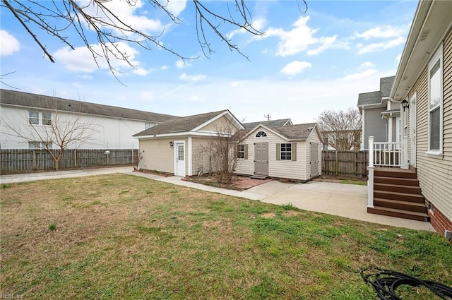 rear view of house with an outbuilding, a patio, a yard, and fence