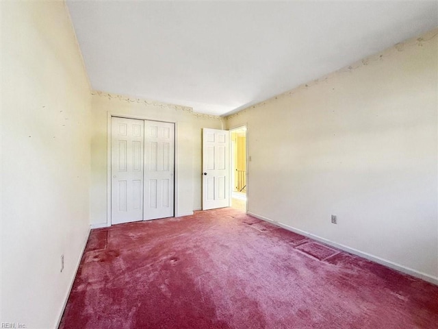 unfurnished bedroom with a closet, carpet flooring, and baseboards