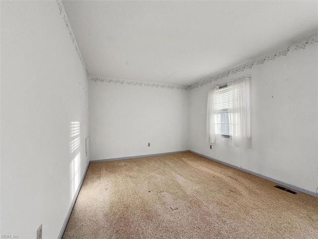 empty room featuring visible vents, light colored carpet, and baseboards