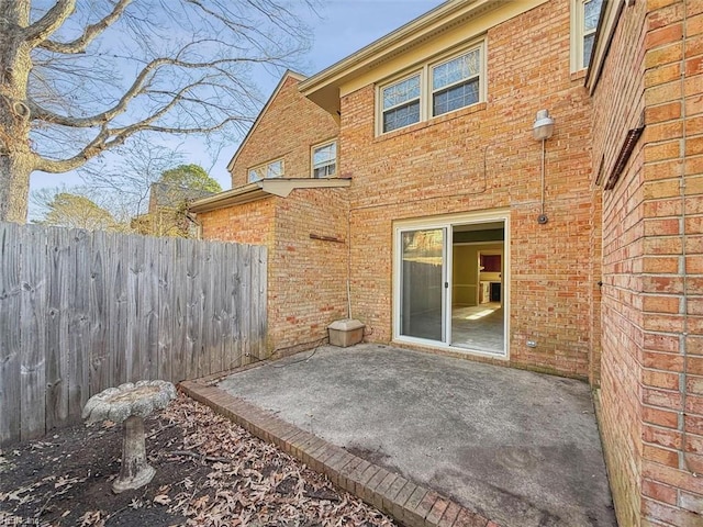 rear view of house featuring brick siding, a patio area, and fence