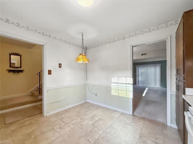 unfurnished room featuring stairs, visible vents, and a wainscoted wall