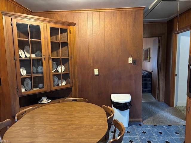 dining area featuring wood walls and dark carpet