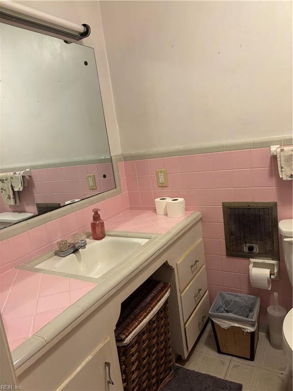 bathroom featuring toilet, tile walls, wainscoting, and vanity