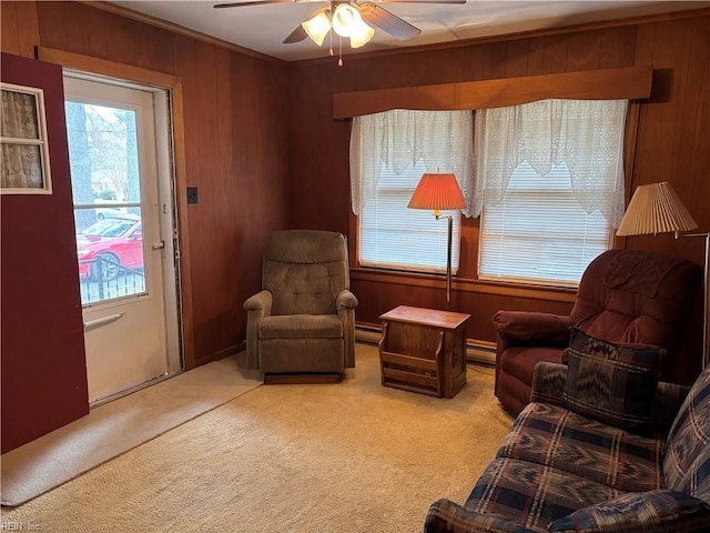 sitting room with ceiling fan, a baseboard radiator, carpet floors, and wood walls