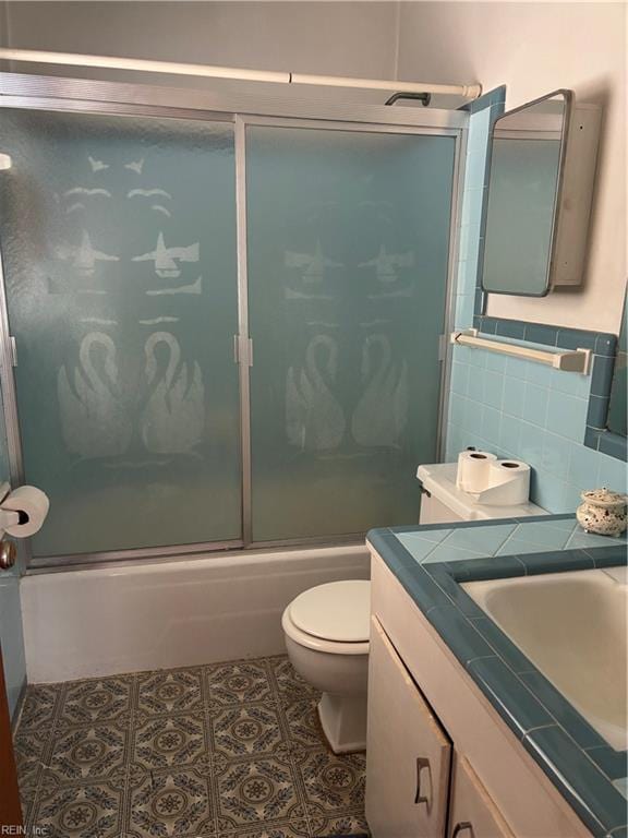 full bathroom featuring vanity, bath / shower combo with glass door, tile patterned flooring, toilet, and tasteful backsplash