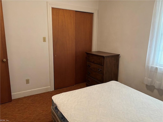 carpeted bedroom featuring a closet and baseboards