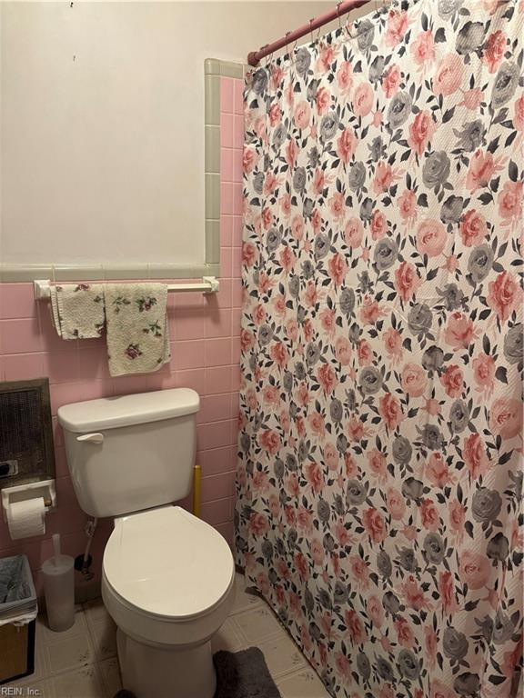 full bathroom featuring curtained shower, tile walls, toilet, and wainscoting