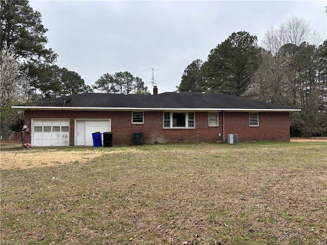 rear view of property with brick siding, cooling unit, an attached garage, and a yard