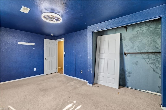 unfurnished bedroom featuring visible vents, carpet, and a textured wall